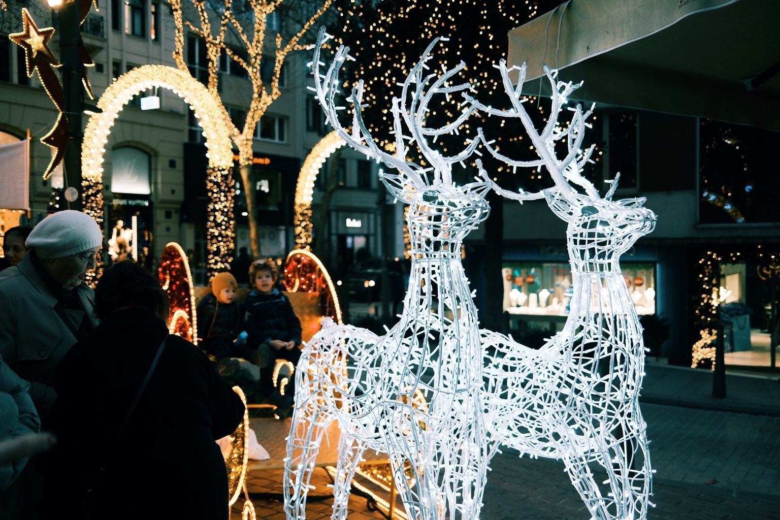 Illuminated reindeer decorations beneath Christmas lights